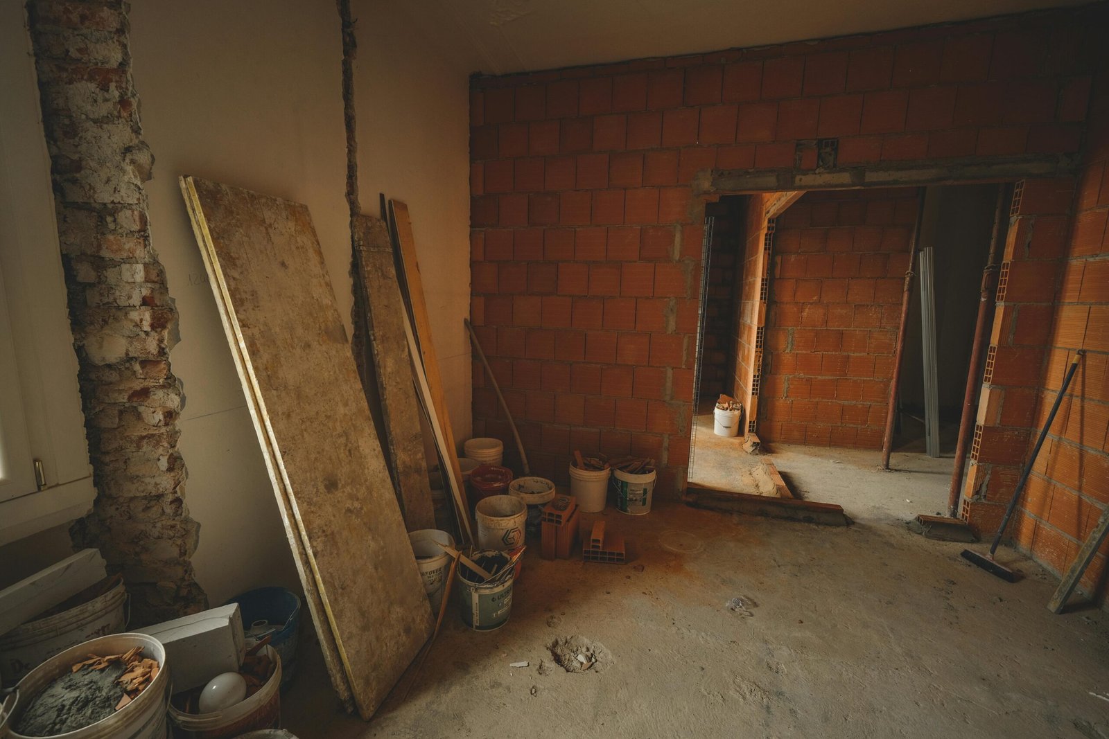 A red brick wall under construction with tools and materials scattered around in a renovation project.