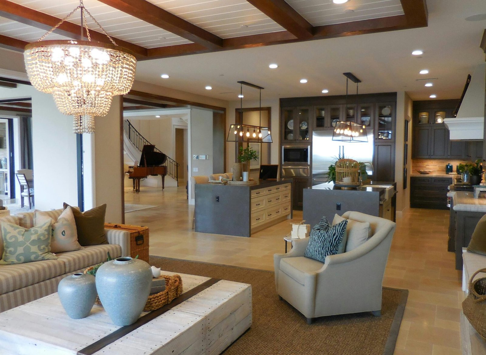 Spacious living room with elegant decor and an open kitchen area, featuring a chandelier and comfortable furnishings.