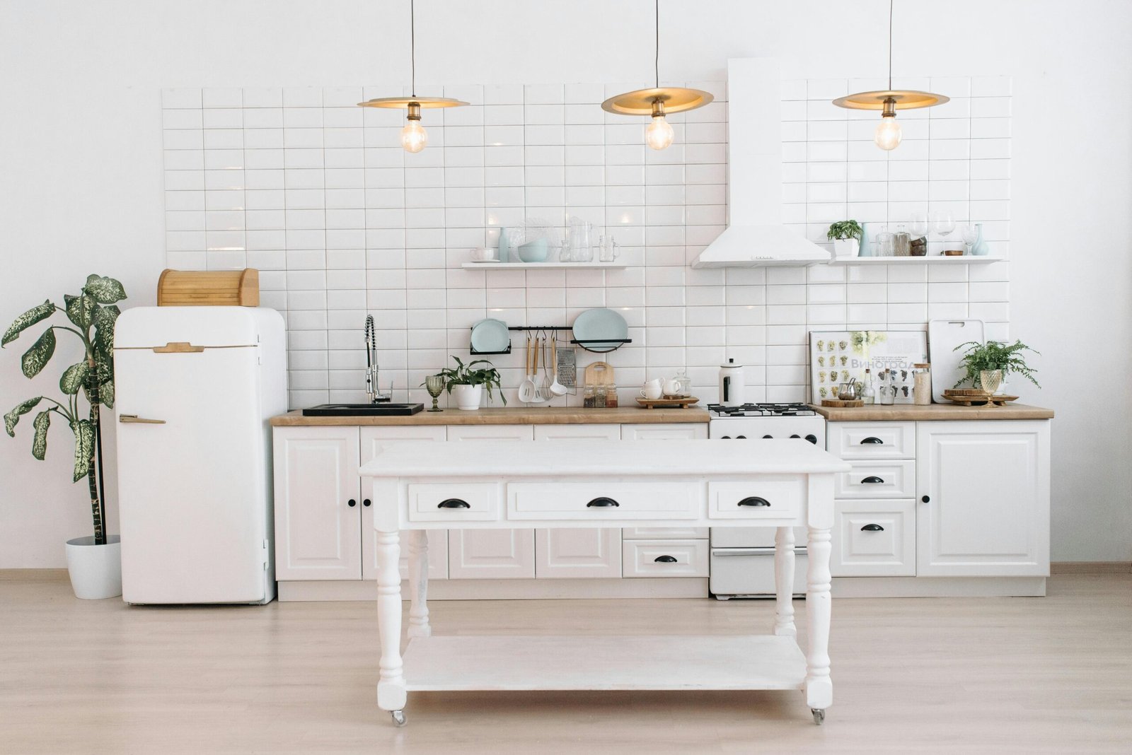 A bright, minimalist kitchen with vintage appliances, plants, and pendant lights.