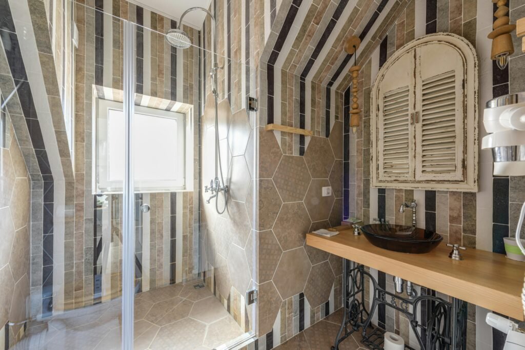 Beautifully designed bathroom featuring stylish tiles, glass shower, and unique sink area.